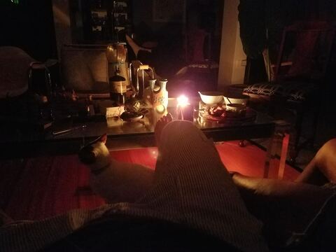 Candlelit interior of Carli's home during Hurricane María's 147-day blackout, with a cat sleeping in the foreground